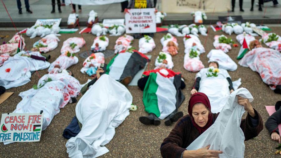 Demonstran pro-Palestina yang mengenakan kain putih tergeletak di tanah di luar Gedung Putih di Washington, AS, 2 Desember 2023. Orang-orang berkumpul dalam solidaritas setelah gencatan senjata sementara antara Israel dan Hamas berakhir awal pekan ini. (REUTERS/Bonnie Cash)