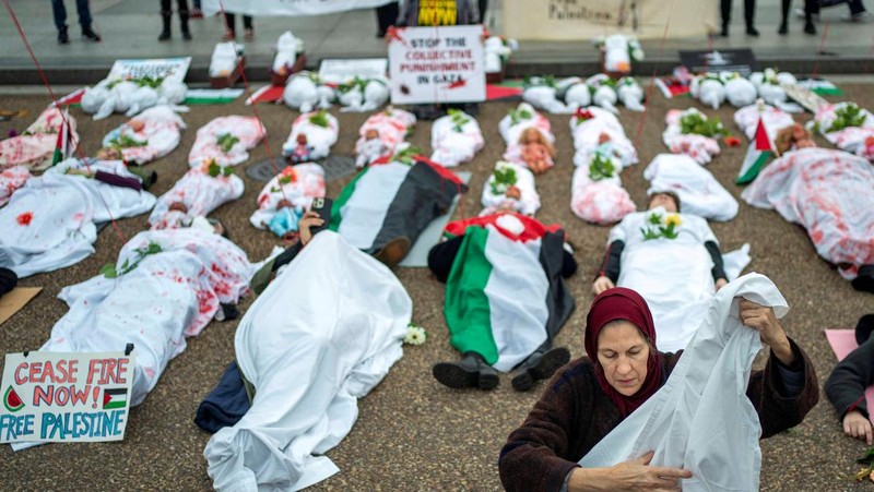 Demonstran pro-Palestina yang mengenakan kain putih tergeletak di tanah di luar Gedung Putih di Washington, AS, 2 Desember 2023. Orang-orang berkumpul dalam solidaritas setelah gencatan senjata sementara antara Israel dan Hamas berakhir awal pekan ini. (REUTERS/Bonnie Cash)