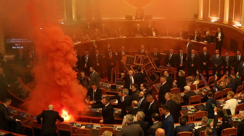 Seorang anggota parlemen dari Partai Demokrat, yang merupakan partaimoposisi terbesar Albania menyalakan bom asap berwarna sebagai tanda protes saat sidang parlemen di Tirana, Albania, Senin (4/12/2023). (REUTERS/Florion Goga)
