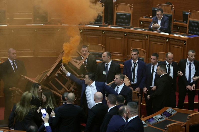 Seorang anggota parlemen dari Partai Demokrat, yang merupakan partaimoposisi terbesar Albania menyalakan bom asap berwarna sebagai tanda protes saat sidang parlemen di Tirana, Albania, Senin (4/12/2023). (REUTERS/Florion Goga) Seorang anggota parlemen dari Partai Demokrat, yang merupakan partaimoposisi terbesar Albania menyalakan bom asap berwarna sebagai tanda protes saat sidang parlemen di Tirana, Albania, Senin (4/12/2023). (REUTERS/Florion Goga)