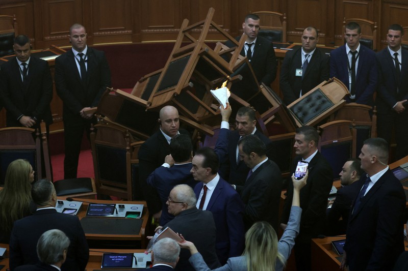 Seorang anggota parlemen dari Partai Demokrat, yang merupakan partaimoposisi terbesar Albania menyalakan bom asap berwarna sebagai tanda protes saat sidang parlemen di Tirana, Albania, Senin (4/12/2023). (REUTERS/Florion Goga)
