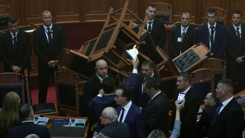 Seorang anggota parlemen dari Partai Demokrat, yang merupakan partaimoposisi terbesar Albania menyalakan bom asap berwarna sebagai tanda protes saat sidang parlemen di Tirana, Albania, Senin (4/12/2023). (REUTERS/Florion Goga)