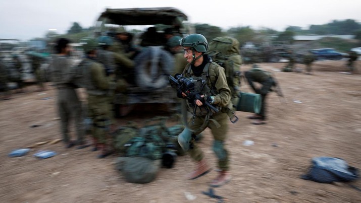Seorang tentara Israel berjalan dengan membawa senjata, di tengah konflik yang sedang berlangsung antara Israel dan kelompok Islam Palestina Hamas, dekat perbatasan Israel dengan Gaza, di Israel selatan, 4 Desember 2023. (REUTERS/Amir Cohen)