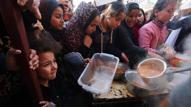 Warga Palestina berebut makanan yang diberikan oleh para sukarelawan, di tengah kekurangan pangan selama konflik antara Israel dan kelompok Islam Palestina Hamas berlanjut, di Rafah, di selatan Jalur Gaza. (REUTERS/Ibraheem Abu Mustafa)