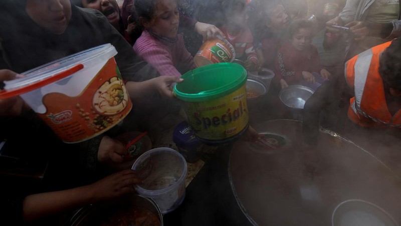 Warga Palestina berebut makanan yang diberikan oleh para sukarelawan, di tengah kekurangan pangan selama konflik antara Israel dan kelompok Islam Palestina Hamas berlanjut, di Rafah, di selatan Jalur Gaza. (REUTERS/Ibraheem Abu Mustafa)