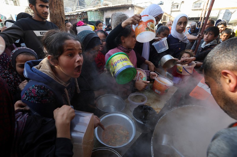 Warga Palestina berebut makanan yang diberikan oleh para sukarelawan, di tengah kekurangan pangan selama konflik antara Israel dan kelompok Islam Palestina Hamas berlanjut, di Rafah, di selatan Jalur Gaza. (REUTERS/Ibraheem Abu Mustafa)