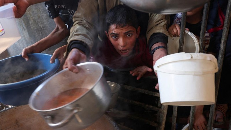 Warga Palestina berebut makanan yang diberikan oleh para sukarelawan, di tengah kekurangan pangan selama konflik antara Israel dan kelompok Islam Palestina Hamas berlanjut, di Rafah, di selatan Jalur Gaza. (REUTERS/Ibraheem Abu Mustafa)