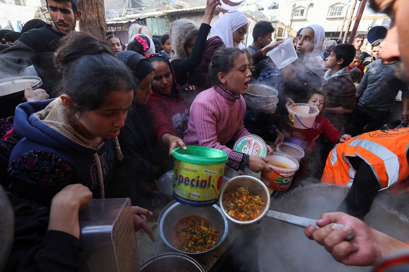 Warga Palestina berebut makanan yang diberikan oleh para sukarelawan, di tengah kekurangan pangan selama konflik antara Israel dan kelompok Islam Palestina Hamas berlanjut, di Rafah, di selatan Jalur Gaza. (REUTERS/Ibraheem Abu Mustafa)