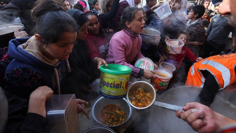 Warga Palestina berebut makanan yang diberikan oleh para sukarelawan, di tengah kekurangan pangan selama konflik antara Israel dan kelompok Islam Palestina Hamas berlanjut, di Rafah, di selatan Jalur Gaza. (REUTERS/Ibraheem Abu Mustafa)
