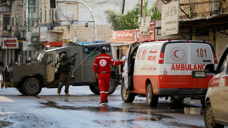 Kendaraan militer Israel memblokir ambulans di jalan selama penggerebekan di Jenin, di tengah konflik yang sedang berlangsung antara Israel dan kelompok Islam Palestina Hamas, di Tepi Barat yang diduduki Israel, 13 Desember 2023. (REUTERS/Raneen Sawafta)