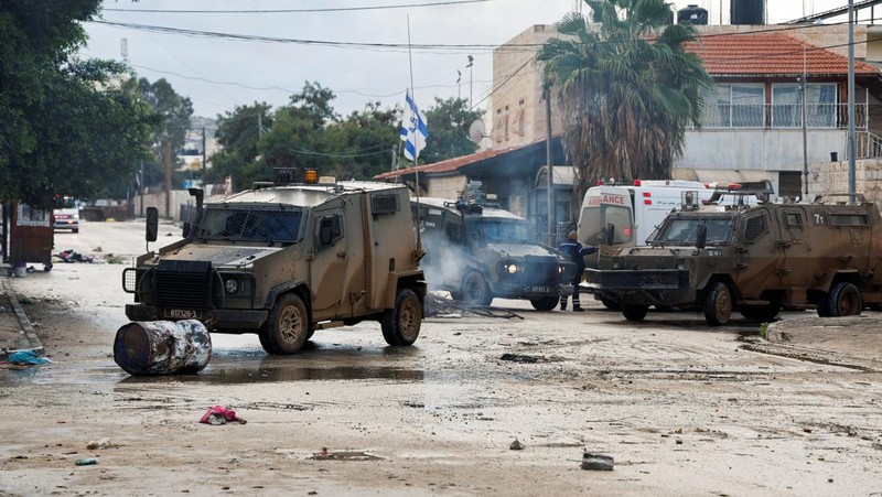 Kendaraan militer Israel memblokir ambulans di jalan selama penggerebekan di Jenin, di tengah konflik yang sedang berlangsung antara Israel dan kelompok Islam Palestina Hamas, di Tepi Barat yang diduduki Israel, 13 Desember 2023. (REUTERS/Raneen Sawafta)