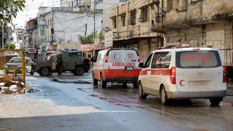 Kendaraan militer Israel memblokir ambulans di jalan selama penggerebekan di Jenin, di tengah konflik yang sedang berlangsung antara Israel dan kelompok Islam Palestina Hamas, di Tepi Barat yang diduduki Israel, 13 Desember 2023. (REUTERS/Raneen Sawafta)