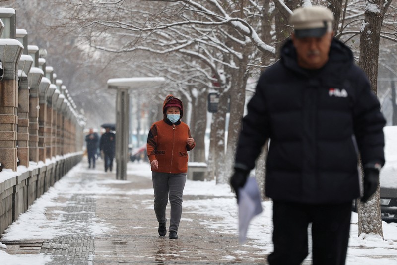 Orang-orang berjalan di jalan di tengah hujan salju di Beijing, Cina 13 Desember 2023. Orang-orang berjalan di jalan di tengah hujan salju di Beijing, Cina 13 Desember 2023. (REUTERS/Tingshu Wang)