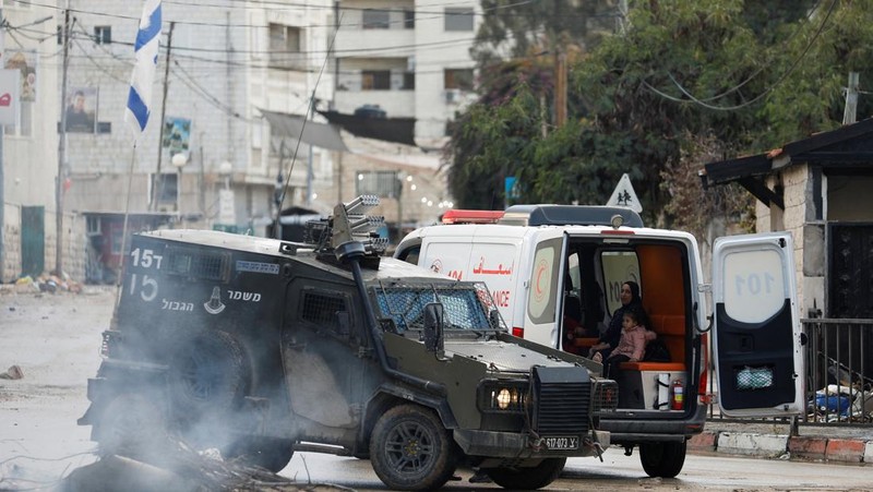Kendaraan militer Israel memblokir ambulans di jalan selama penggerebekan di Jenin, di tengah konflik yang sedang berlangsung antara Israel dan kelompok Islam Palestina Hamas, di Tepi Barat yang diduduki Israel, 13 Desember 2023. (REUTERS/Raneen Sawafta)