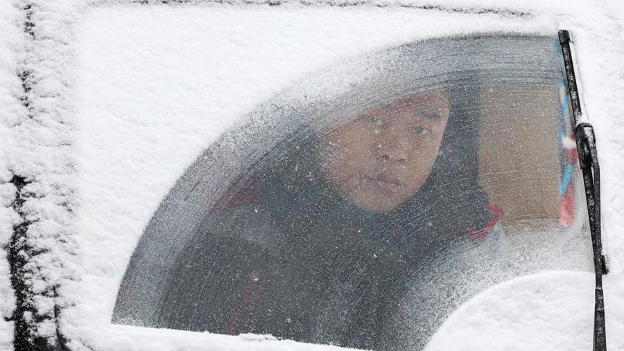 Orang-orang berjalan di jalan di tengah hujan salju di Beijing, Cina 13 Desember 2023. (REUTERS/Tingshu Wang)