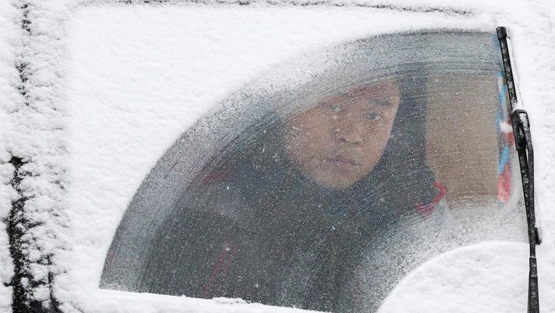 Orang-orang berjalan di jalan di tengah hujan salju di Beijing, Cina 13 Desember 2023. (REUTERS/Tingshu Wang)