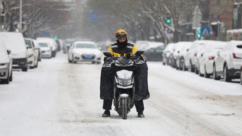 Orang-orang berjalan di jalan di tengah hujan salju di Beijing, Cina 13 Desember 2023. (REUTERS/Tingshu Wang)
