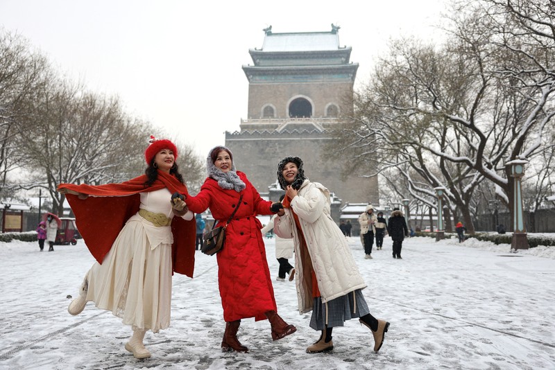 Orang-orang berjalan di jalan di tengah hujan salju di Beijing, Cina 13 Desember 2023. (REUTERS/Tingshu Wang)