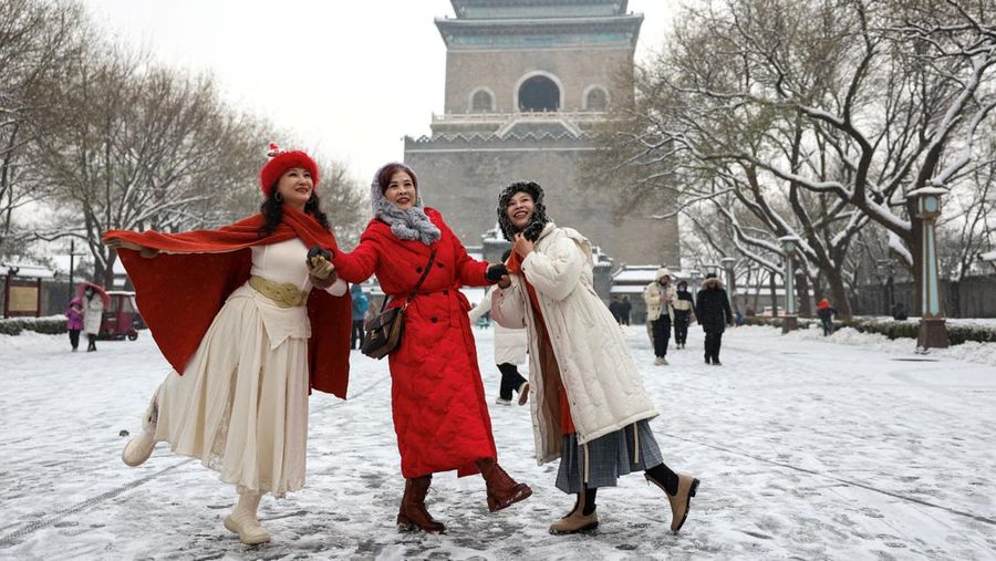 Orang-orang berjalan di jalan di tengah hujan salju di Beijing, Cina 13 Desember 2023. (REUTERS/Tingshu Wang)