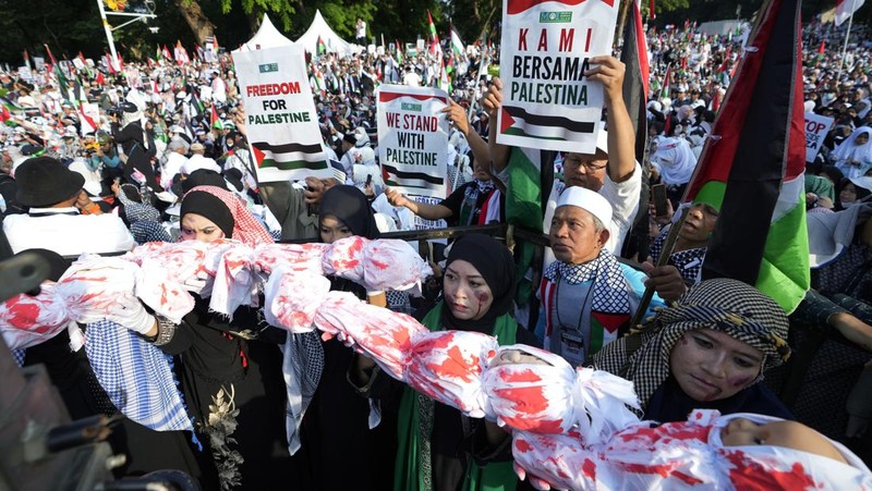 Sejumlah massa aksi membawa replika jenazah anak-anak saat melakukan unjuk rasa di depan Kedubes Amerika Serikat (AS), Jalan Medan Merdeka Selatan, Jakarta, Minggu (17/12/2023). (AP Photo/Achmad Ibrahim)
