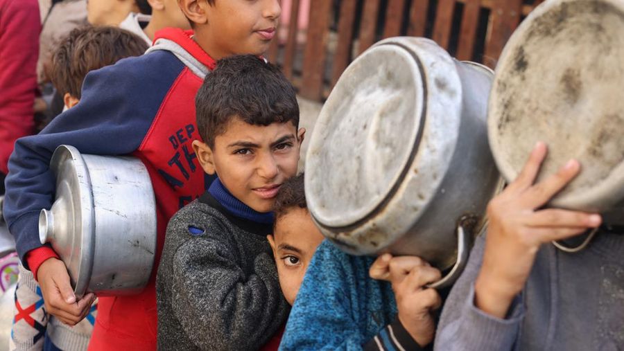 Anak-anak Palestina memegang panci saat mereka mengantri untuk menerima makanan yang dimasak oleh dapur amal, di tengah kekurangan pasokan makanan, saat konflik antara Israel dan Hamas berlanjut, di Rafah di selatan Jalur Gaza 14 Desember 2023. (REUTERS/Saleh Salem)