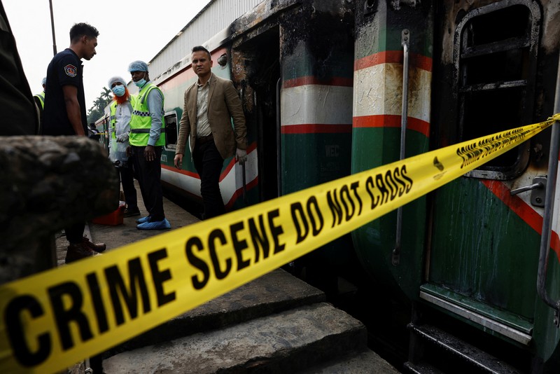 Anggota Unit TKP memeriksa kereta penumpang yang dibakar selama pemogokan nasional yang diserukan oleh Partai Nasionalis Bangladesh, menjelang pemilihan umum, di Dhaka, Bangladesh, 19 Desember 2023. (REUTERS/Mohammad Ponir Hossain)