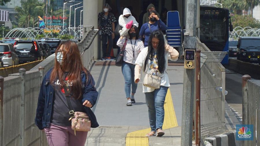 Pejalan kaki menggunakan payung untuk menghindari terik matahari di kawasan Jembatan Pinisi di halte busway Karet, Jakarta, Selasa (19/12/2023). (²©²ÊÍøÕ¾/Muhammad Sabki)