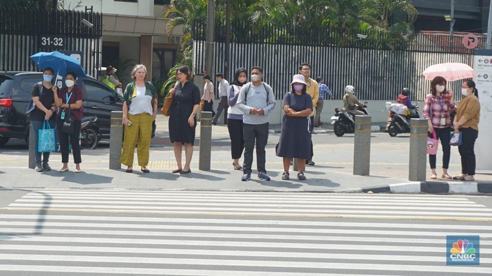 Pejalan kaki menggunakan payung untuk menghindari terik matahari di kawasan Jembatan Pinisi di halte busway Karet, Jakarta, Selasa (19/12/2023). (CNBC Indonesia/Muhammad Sabki)