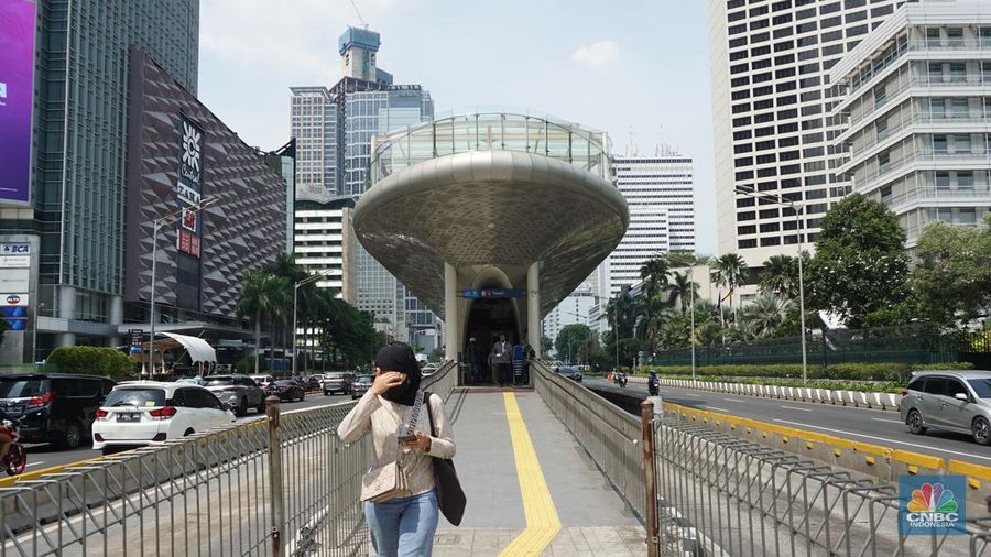 Pejalan kaki menggunakan payung untuk menghindari terik matahari di kawasan Jembatan Pinisi di halte busway Karet, Jakarta, Selasa (19/12/2023). (վ/Muhammad Sabki)