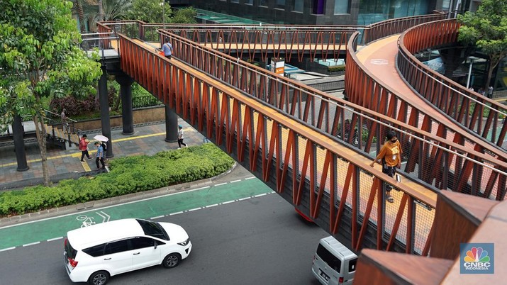 Pejalan kaki menggunakan payung untuk menghindari terik matahari di kawasan Jembatan Pinisi di halte busway Karet, Jakarta, Selasa (19/12/2023). (CNBC Indonesia/Muhammad Sabki)