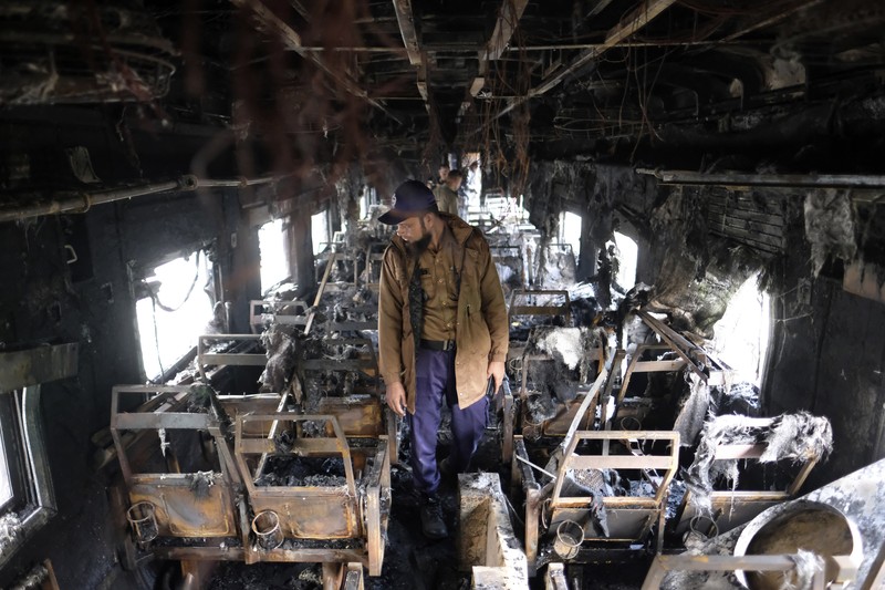 Anggota Unit TKP memeriksa kereta penumpang yang dibakar selama pemogokan nasional yang diserukan oleh Partai Nasionalis Bangladesh, menjelang pemilihan umum, di Dhaka, Bangladesh, 19 Desember 2023. (REUTERS/Mohammad Ponir Hossain)