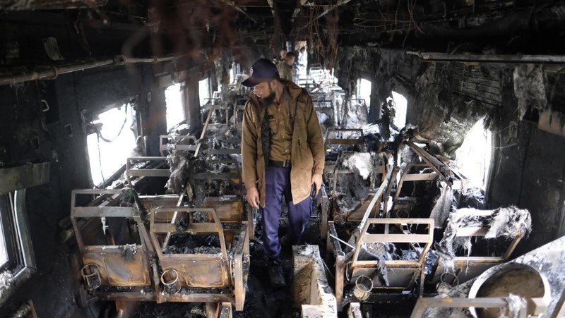Anggota Unit TKP memeriksa kereta penumpang yang dibakar selama pemogokan nasional yang diserukan oleh Partai Nasionalis Bangladesh, menjelang pemilihan umum, di Dhaka, Bangladesh, 19 Desember 2023. (REUTERS/Mohammad Ponir Hossain)