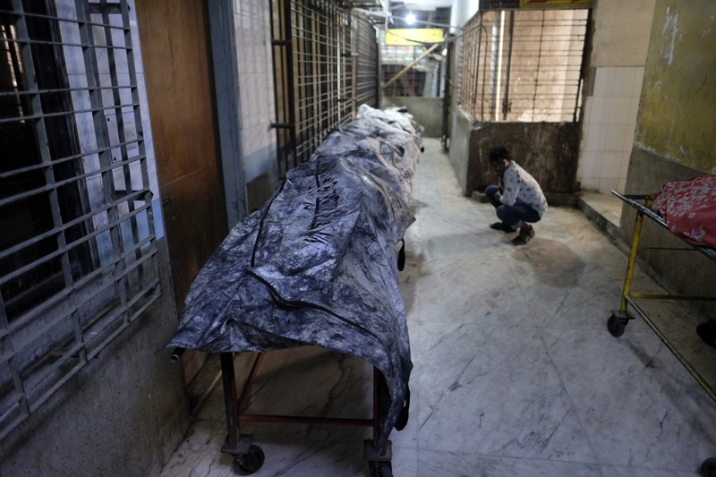 Anggota Unit TKP memeriksa kereta penumpang yang dibakar selama pemogokan nasional yang diserukan oleh Partai Nasionalis Bangladesh, menjelang pemilihan umum, di Dhaka, Bangladesh, 19 Desember 2023. (REUTERS/Mohammad Ponir Hossain)
