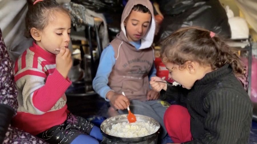 Anak-anak Palestina memegang panci saat mereka mengantri untuk menerima makanan yang dimasak oleh dapur amal, di tengah kekurangan pasokan makanan, saat konflik antara Israel dan Hamas berlanjut, di Rafah di selatan Jalur Gaza 14 Desember 2023. (REUTERS/Saleh Salem)