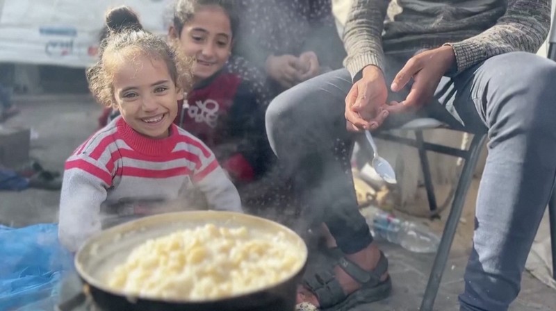 Anak-anak Palestina memegang panci saat mereka mengantri untuk menerima makanan yang dimasak oleh dapur amal, di tengah kekurangan pasokan makanan, saat konflik antara Israel dan Hamas berlanjut, di Rafah di selatan Jalur Gaza 14 Desember 2023. (REUTERS/Saleh Salem)