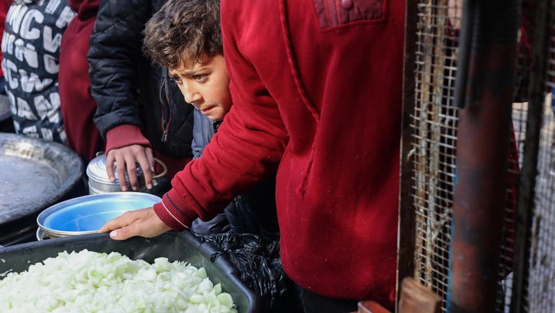 Anak-anak Palestina memegang panci saat mereka mengantri untuk menerima makanan yang dimasak oleh dapur amal, di tengah kekurangan pasokan makanan, saat konflik antara Israel dan Hamas berlanjut, di Rafah di selatan Jalur Gaza 14 Desember 2023. (REUTERS/Saleh Salem)