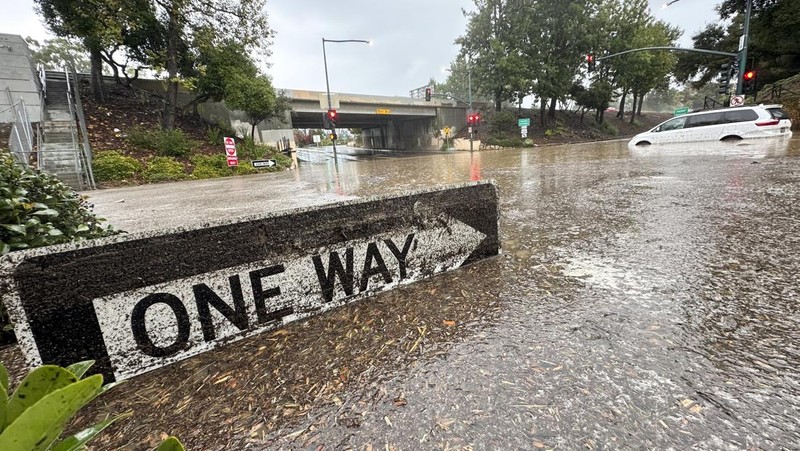 Air banjir mencapai puncak rambu jalan dekat jembatan layang saat hujan turun, Kamis, 21 Desember 2023, di Santa Barbara, California. (AP Photo/Eugene Garcia)