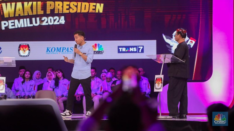 Calon Wakil Presiden Nomor Urut 2 Gibran Rakabuming Raka tiba-tiba keluar dari podium dan mendekati Calon Wakil Presiden Nomor Urut 3 Mahfud MD. Gibran menjelaskan soal rasio pajak ke Mahfud MD. (CNBC Indonesia/Faisal Rahman)