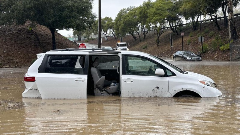 Air banjir mencapai puncak rambu jalan dekat jembatan layang saat hujan turun, Kamis, 21 Desember 2023, di Santa Barbara, California. (AP Photo/Eugene Garcia)