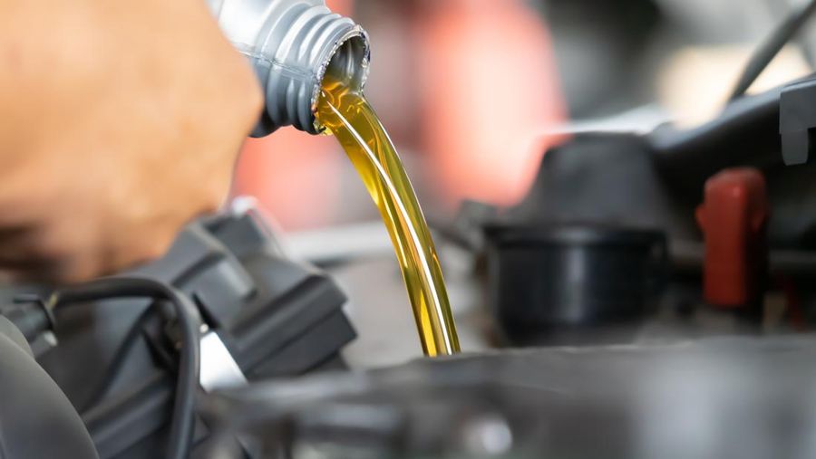 Pouring engine oil to car engine. Fresh oil poured during an oil change to a car.