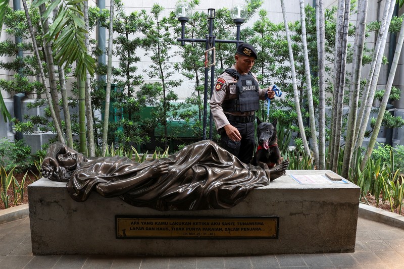A police officer with a sniffer dog inspects Jakarta Cathedral ahead of the Christmas Mass in Jakarta, Indonesia, December 24, 2023. REUTERS/Ajeng Dinar Ulfiana