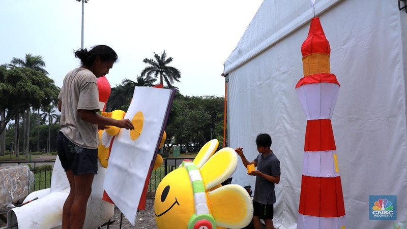 Pekerja seni menyelesaikan dekorasi untuk mobil hias yang akan digunakan untuk Jakarta karnaval sambut tahun baru 2024 di Monas, Jakarta, Rabu, (27/12/2023). (CNBC Indonesia/Muhammad Sabki)