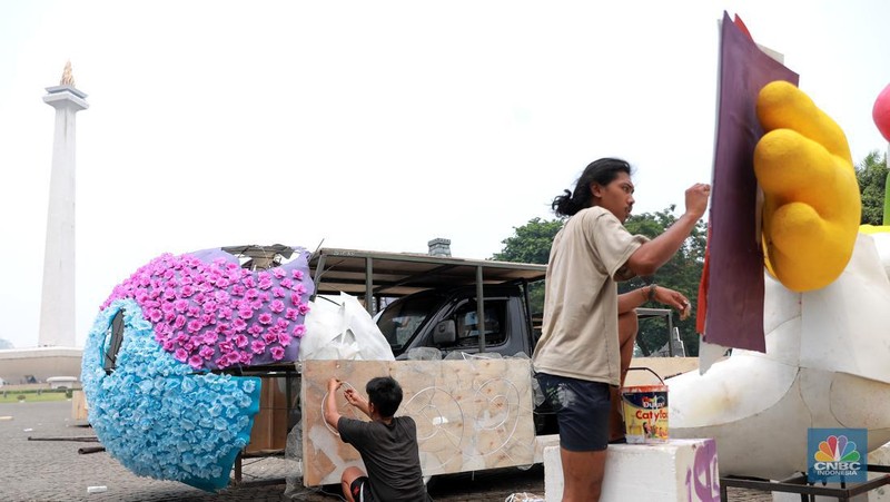 Pekerja seni menyelesaikan dekorasi untuk mobil hias yang akan digunakan untuk Jakarta karnaval sambut tahun baru 2024 di Monas, Jakarta, Rabu, (27/12/2023). (CNBC Indonesia/Muhammad Sabki)