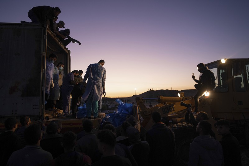 Petugas medis membongkar jenazah warga Palestina yang tewas dalam pertempuran dengan Israel dan diserahkan oleh militer Israel saat pemakaman massal di Rafah, Jalur Gaza, Selasa, 26 Desember 2023. (AP Photo/Fatima Shbair)