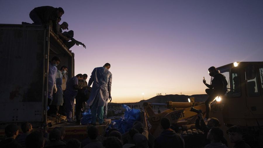 Petugas medis membongkar jenazah warga Palestina yang tewas dalam pertempuran dengan Israel dan diserahkan oleh militer Israel saat pemakaman massal di Rafah, Jalur Gaza, Selasa, 26 Desember 2023. (AP Photo/Fatima Shbair)