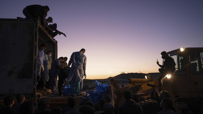 Petugas medis membongkar jenazah warga Palestina yang tewas dalam pertempuran dengan Israel dan diserahkan oleh militer Israel saat pemakaman massal di Rafah, Jalur Gaza, Selasa, 26 Desember 2023. (AP Photo/Fatima Shbair)