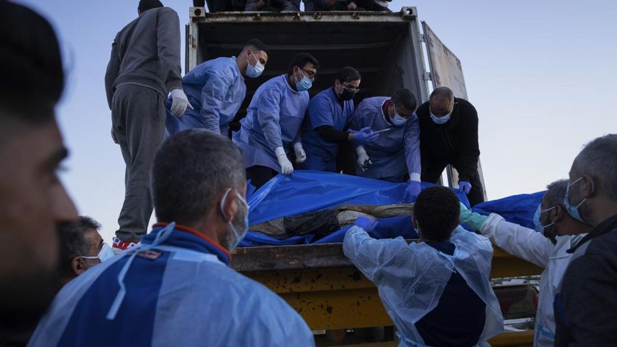 Petugas medis membongkar jenazah warga Palestina yang tewas dalam pertempuran dengan Israel dan diserahkan oleh militer Israel saat pemakaman massal di Rafah, Jalur Gaza, Selasa, 26 Desember 2023. (AP Photo/Fatima Shbair)
