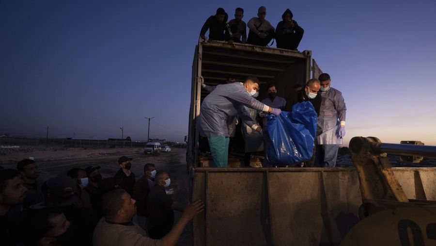 Petugas medis membongkar jenazah warga Palestina yang tewas dalam pertempuran dengan Israel dan diserahkan oleh militer Israel saat pemakaman massal di Rafah, Jalur Gaza, Selasa, 26 Desember 2023. (AP Photo/Fatima Shbair)