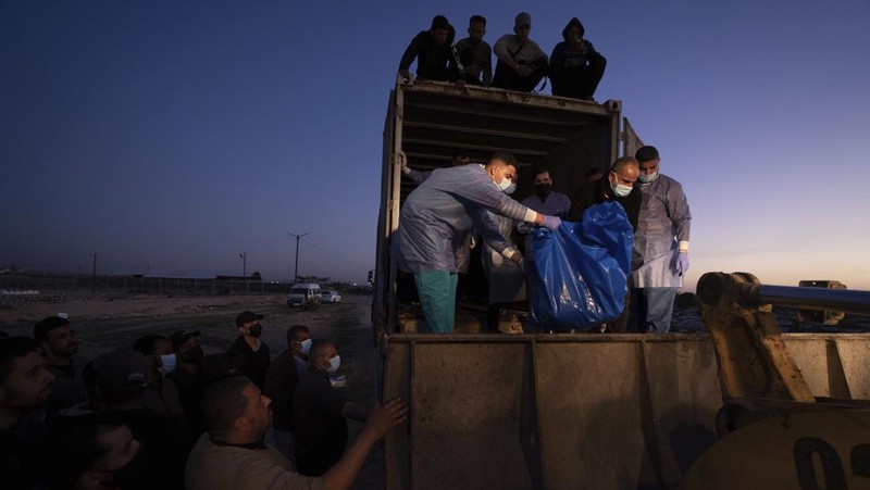 Petugas medis membongkar jenazah warga Palestina yang tewas dalam pertempuran dengan Israel dan diserahkan oleh militer Israel saat pemakaman massal di Rafah, Jalur Gaza, Selasa, 26 Desember 2023. (AP Photo/Fatima Shbair)