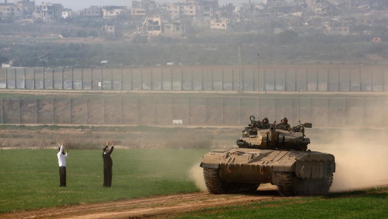 Pria Yahudi ultra-Ortodoks memberi isyarat saat tank Israel melakukan manuver di dekat perbatasan Israel-Gaza, di tengah konflik yang sedang berlangsung antara Israel dan kelompok Islam Palestina Hamas, di Israel selatan, 27 Desember 2023. (REUTERS/Amir Cohen)